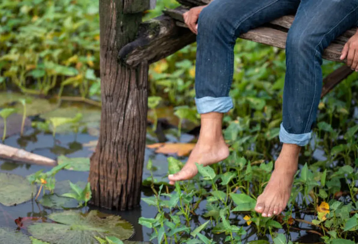 Bare feet resting above calm water, representing reflection and presence