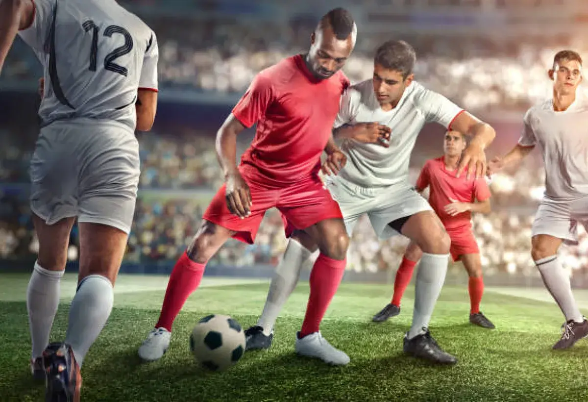 Soccer players battling for ball in front of massive stadium crowd