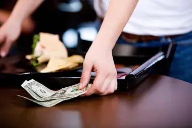 American restaurant server receiving a tip from a customer.
