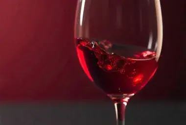 swirling red wine in clear glass on wooden table