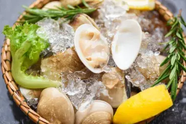Fresh little neck clams on ice with lemon and sea salt.