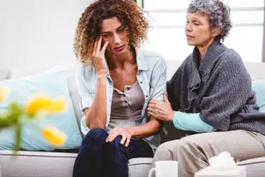 Aging caregiver supporting elderly parent while reflecting on her own future